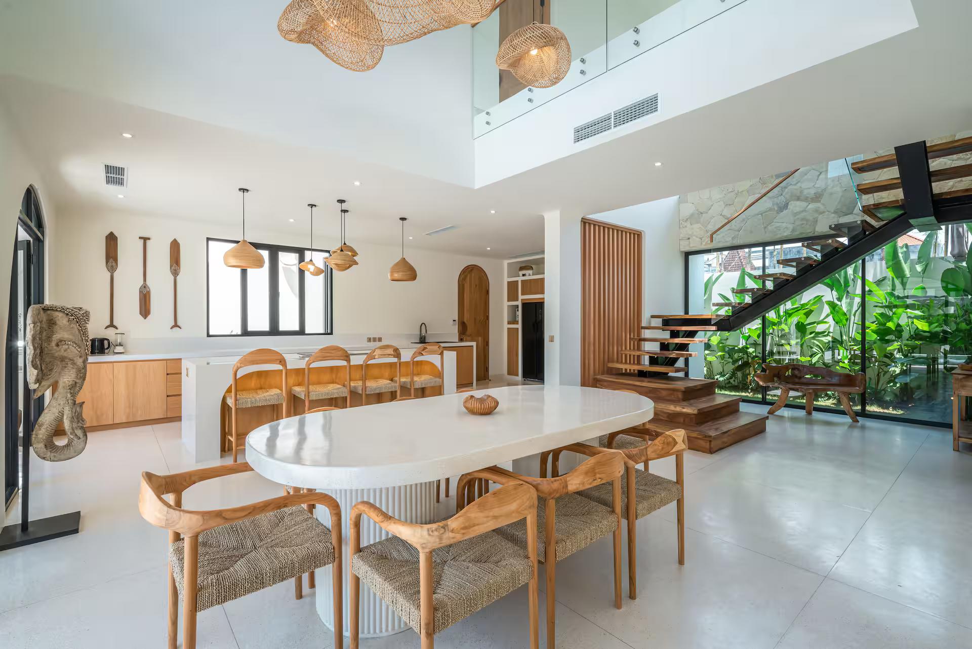 Oval fluted dining table and rattan chairs under woven pendants in the double-height room