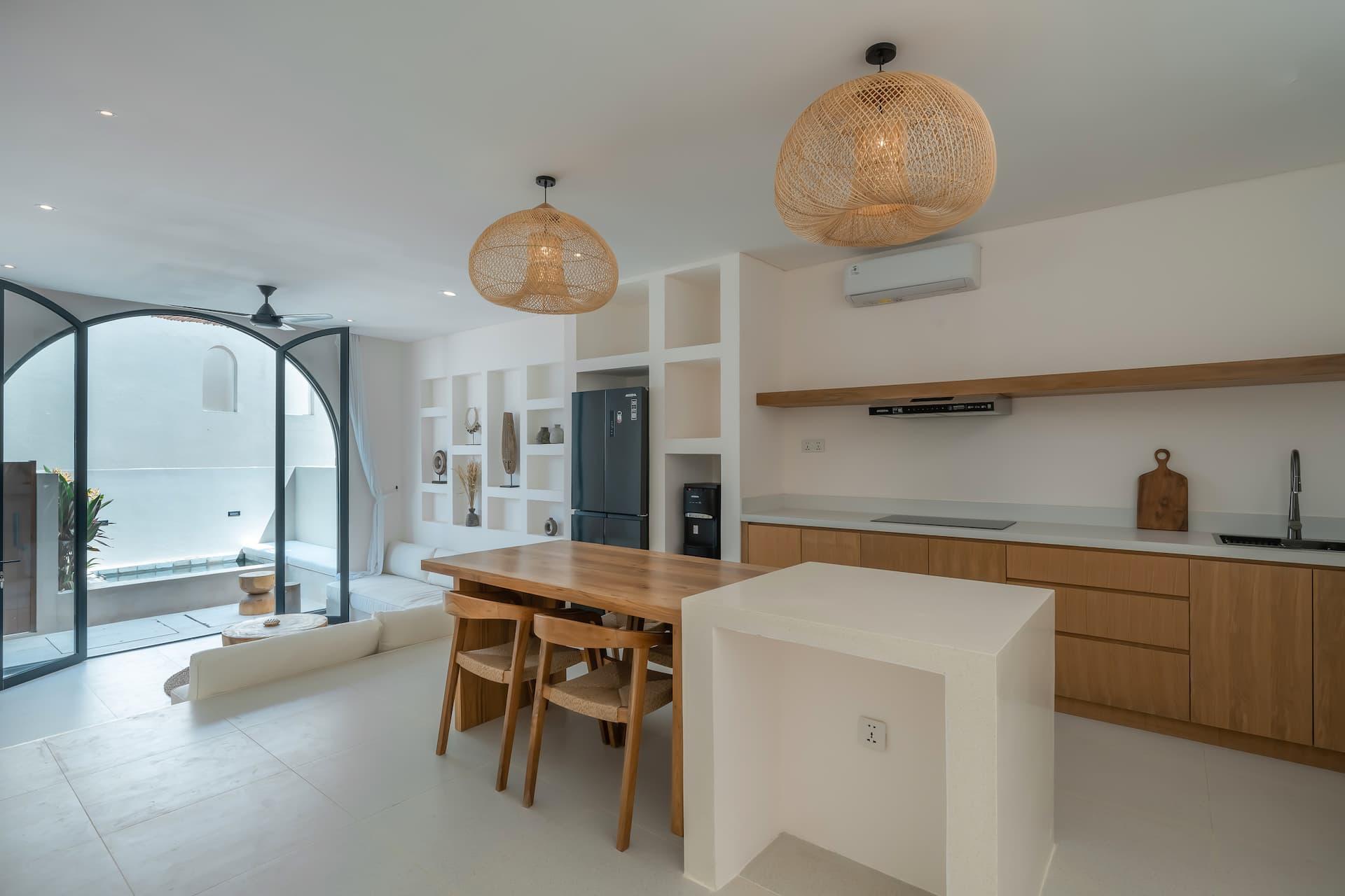 Timber dining table, white island and wood kitchen beside the arched doors to the pool