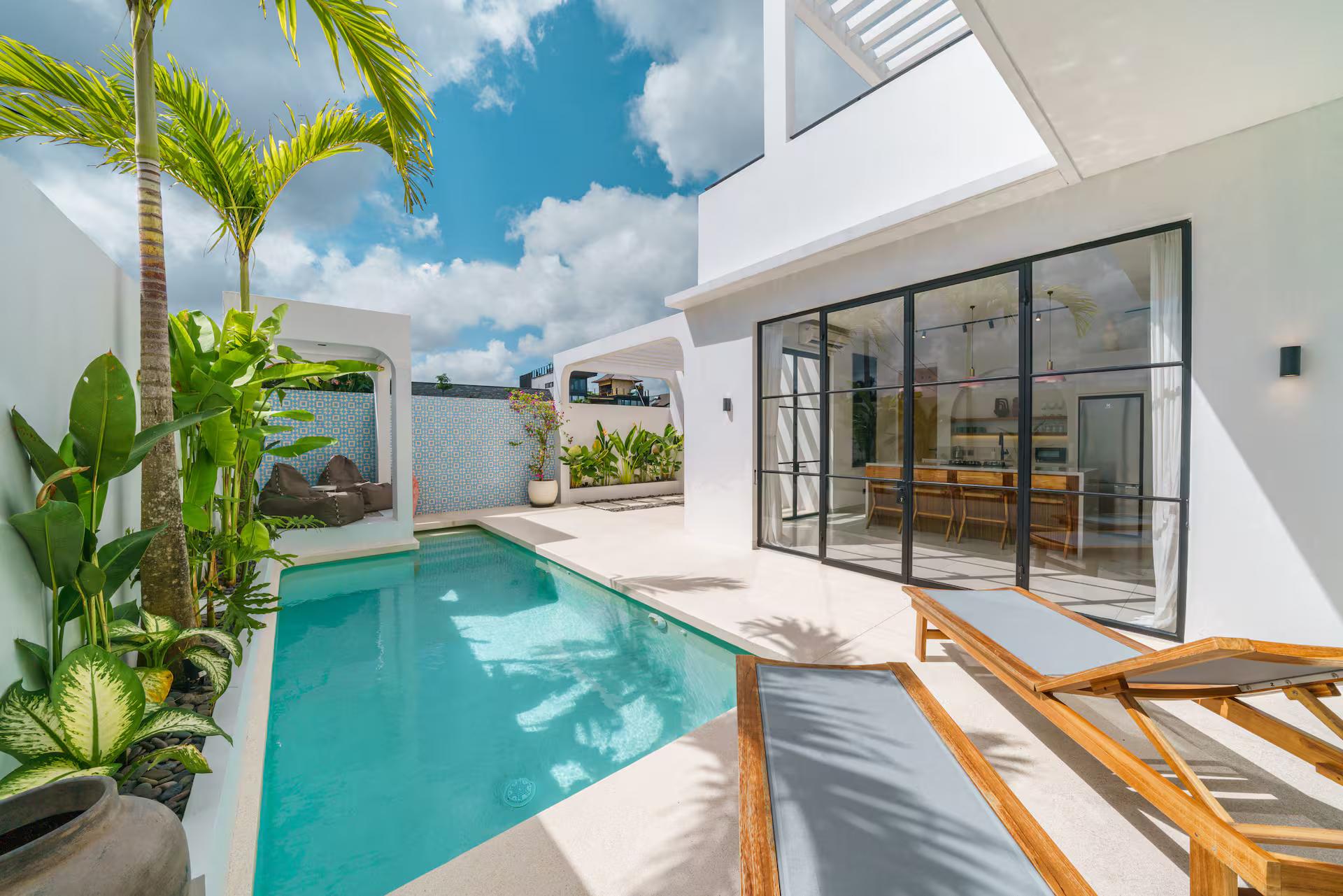 The pool courtyard at Casa Brezza from the far end, palms against the white parapet