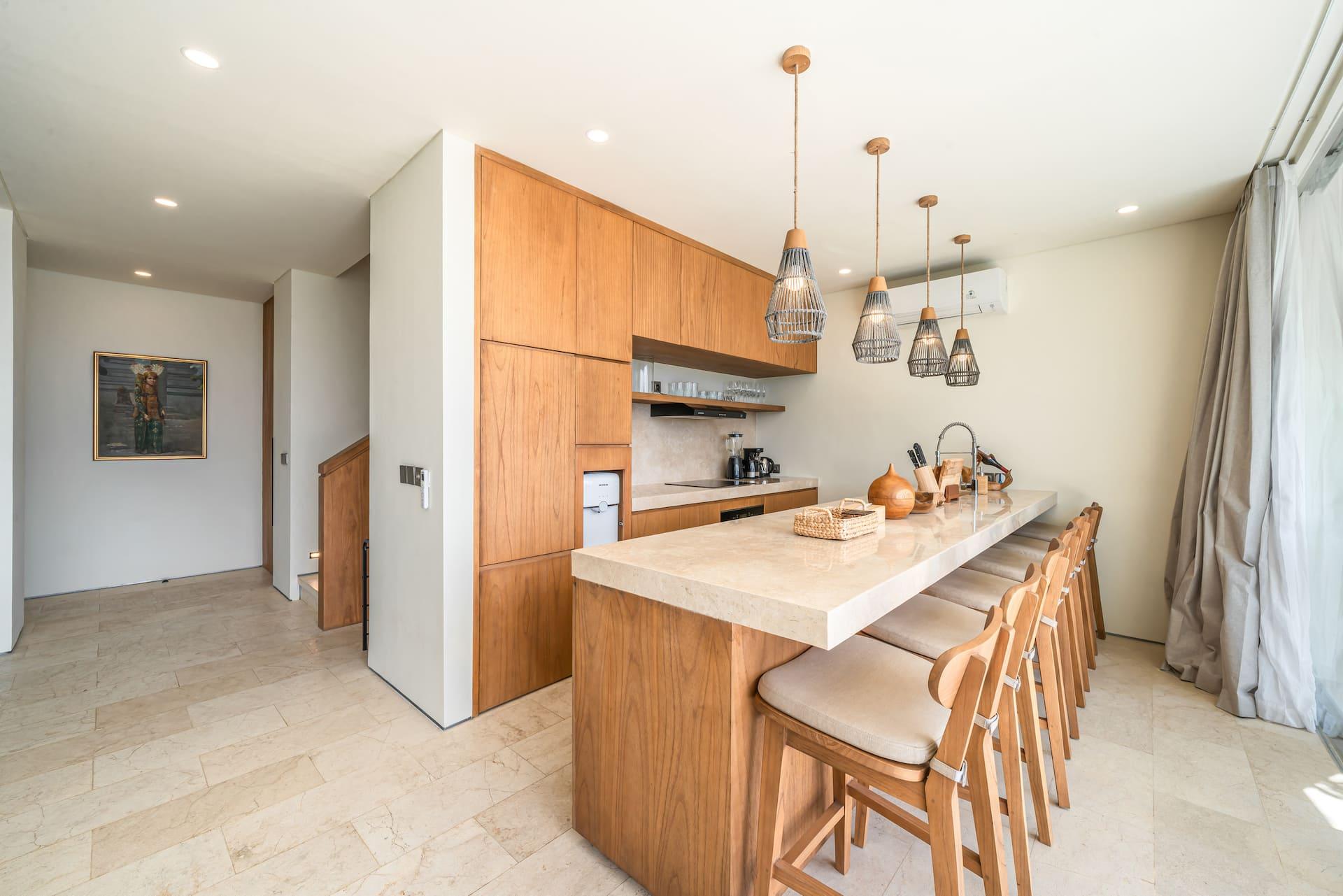 Long stone-topped breakfast bar with timber stools and woven pendants in the kitchen