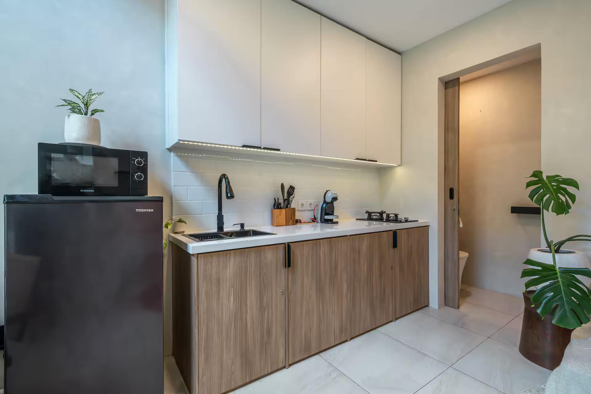 Fridge, microwave and gas hob along the timber-fronted kitchen wall at Casadou