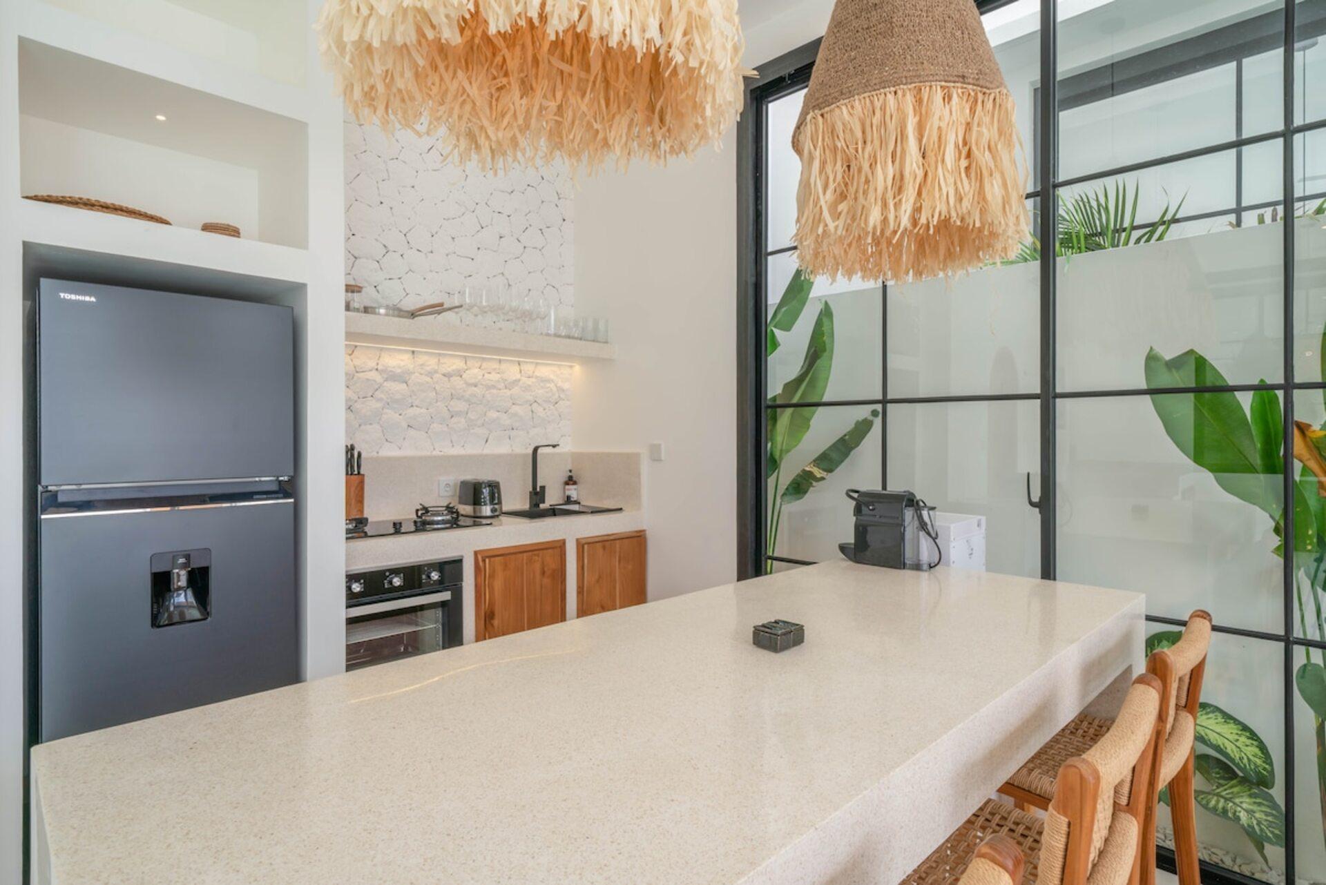Kitchen island in pale terrazzo at Villa Polanco, oven, hob and tall refrigerator