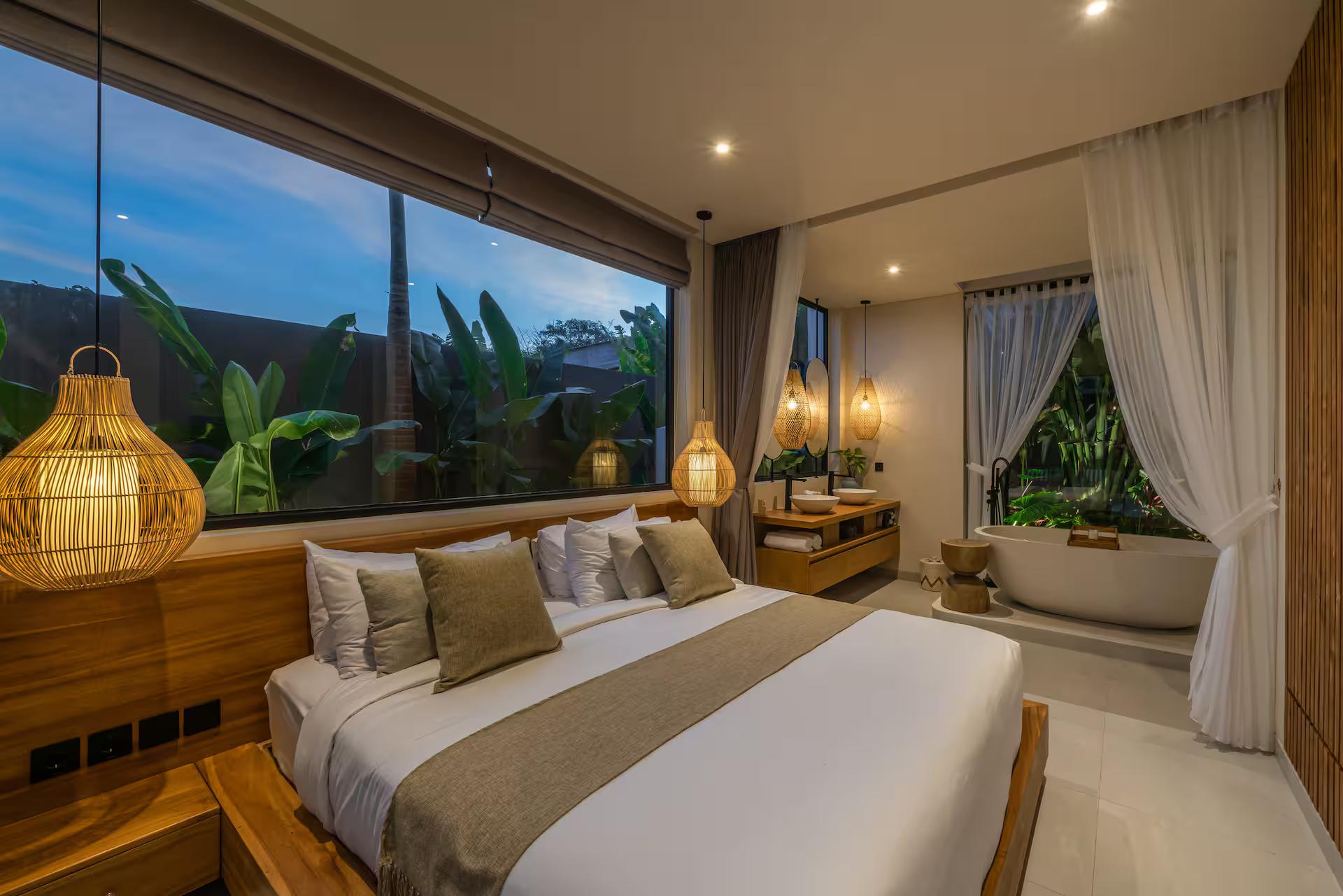 Second bedroom with a wall of glass to the garden and a soaking tub set in the corner