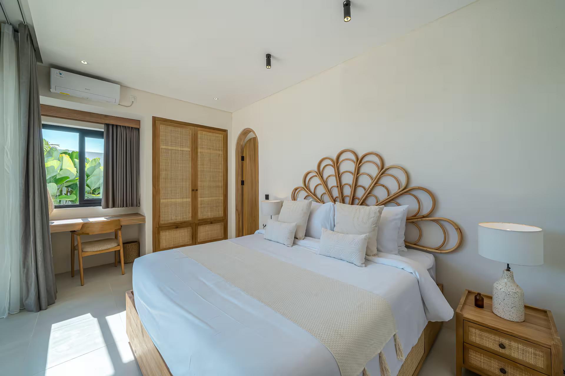 Bedroom with a tall fan-shaped rattan headboard, dressing table and arched timber wardrobes