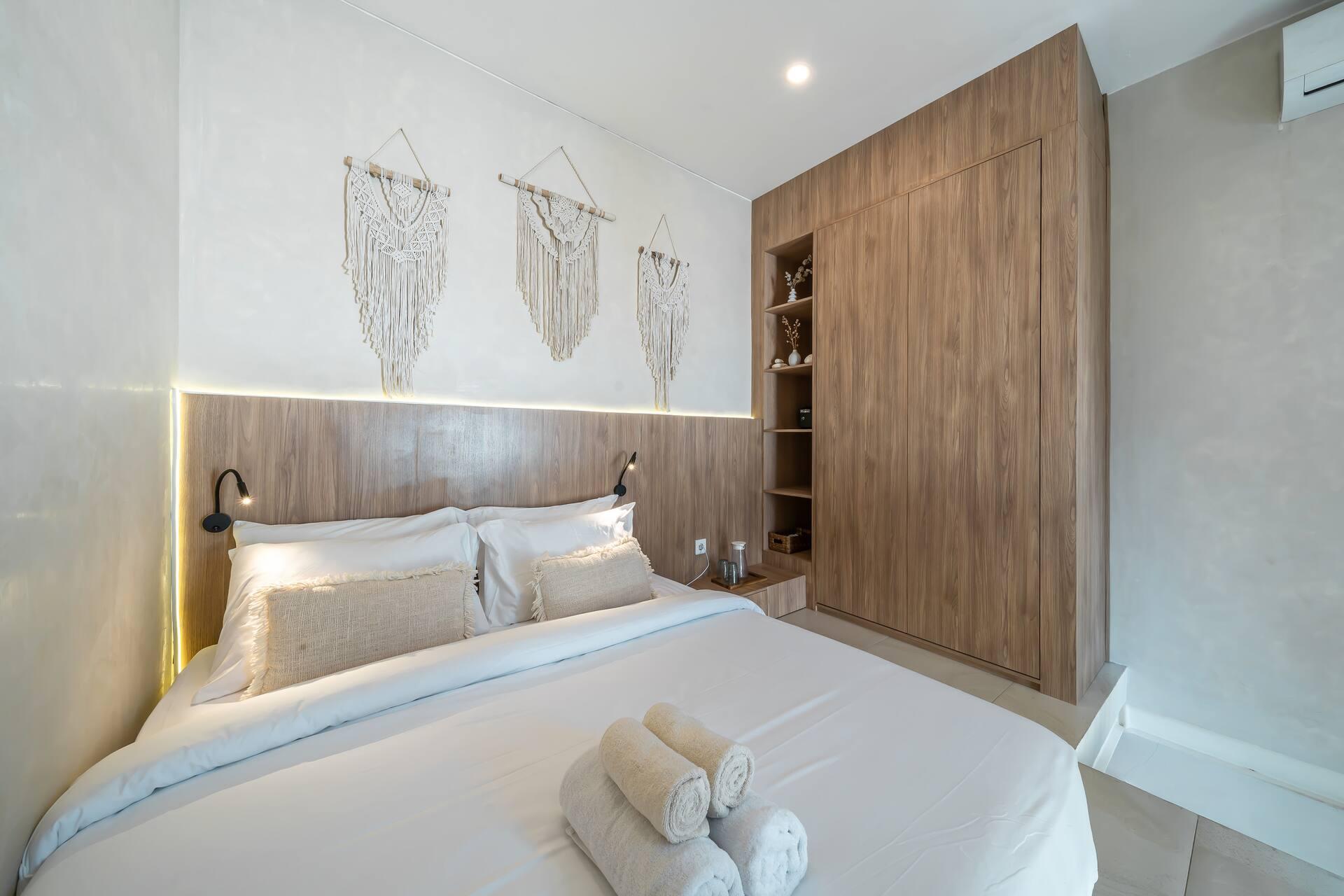 King bed against a lit timber headboard, macrame hangings and built-in shelving