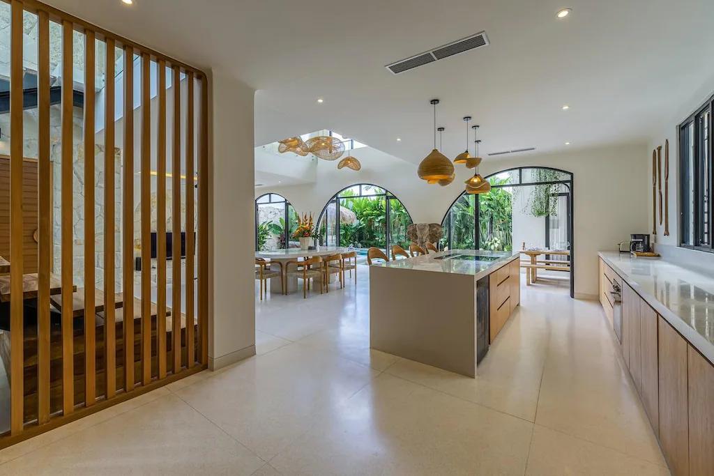 Kitchen corridor at Villa Bimini seen past a timber-slat screen, island and arched windows
