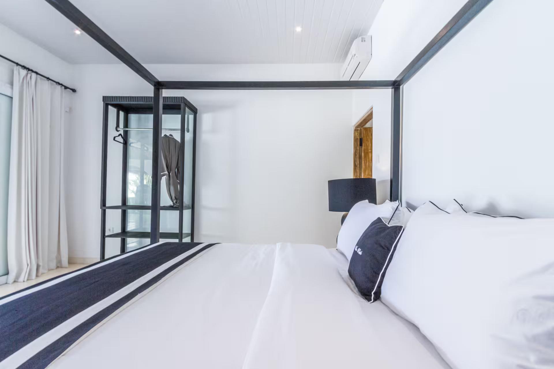 Four-poster bed at Villa Kusuma against black-framed glazing and white walls