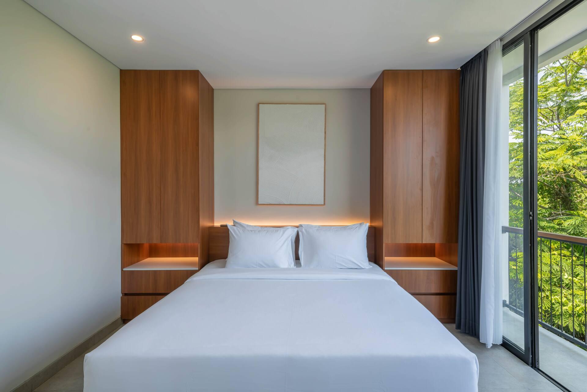 Second king bedroom lined in timber joinery with concealed shelf lighting either side