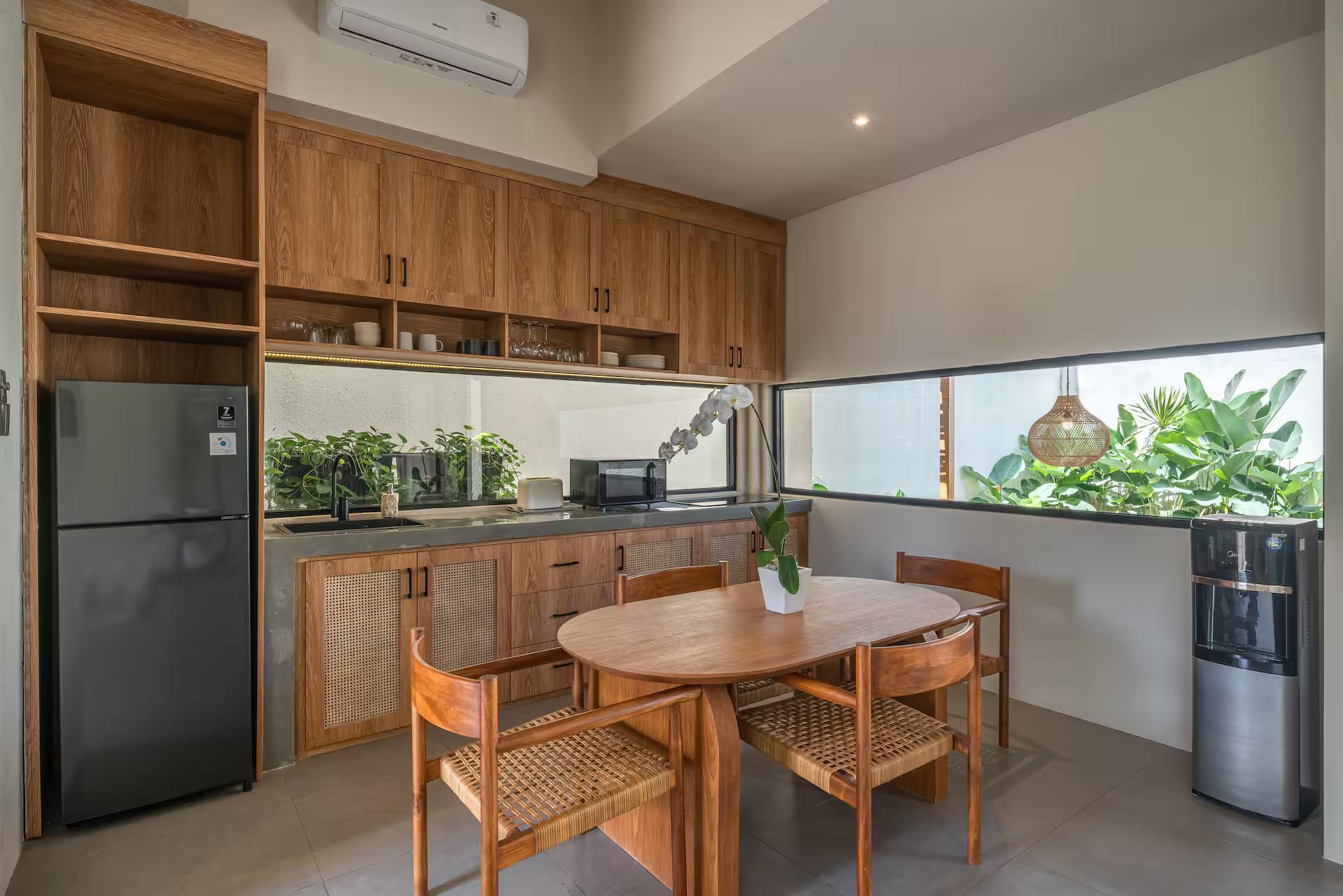 Timber kitchen with a black refrigerator, microwave and water dispenser beside the dining table