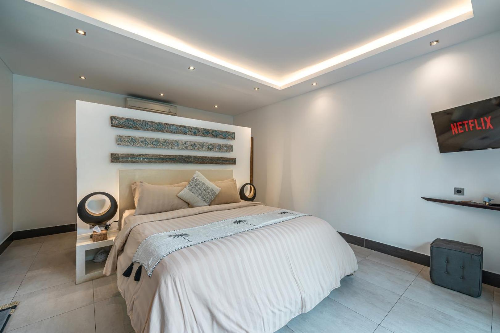 Bedroom with a pale striped headboard panel and a wall-mounted television