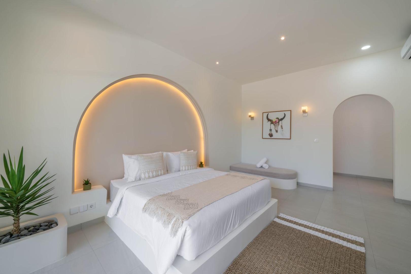 King bed in an arched headboard niche lit from within its plaster cove