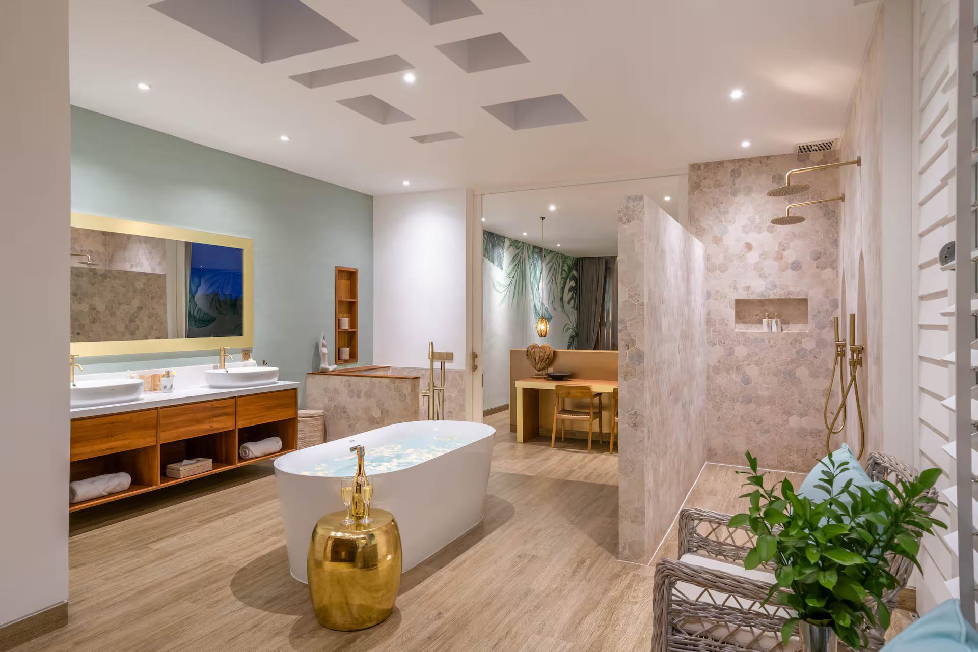 Freestanding tub with a brass filler, travertine walls and the shower beyond