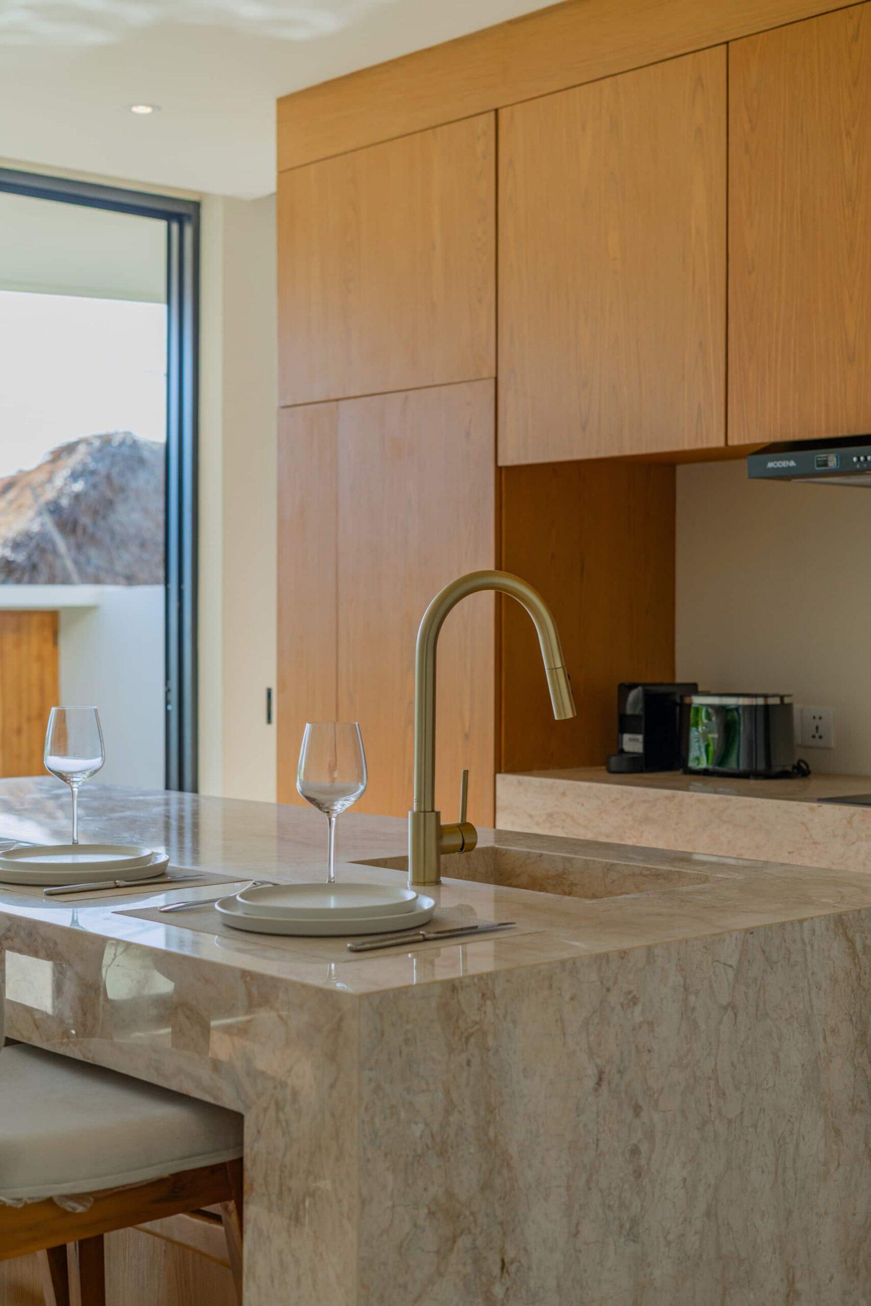 Oak kitchen joinery and a brass tap over the honed stone counter at Villa Amber
