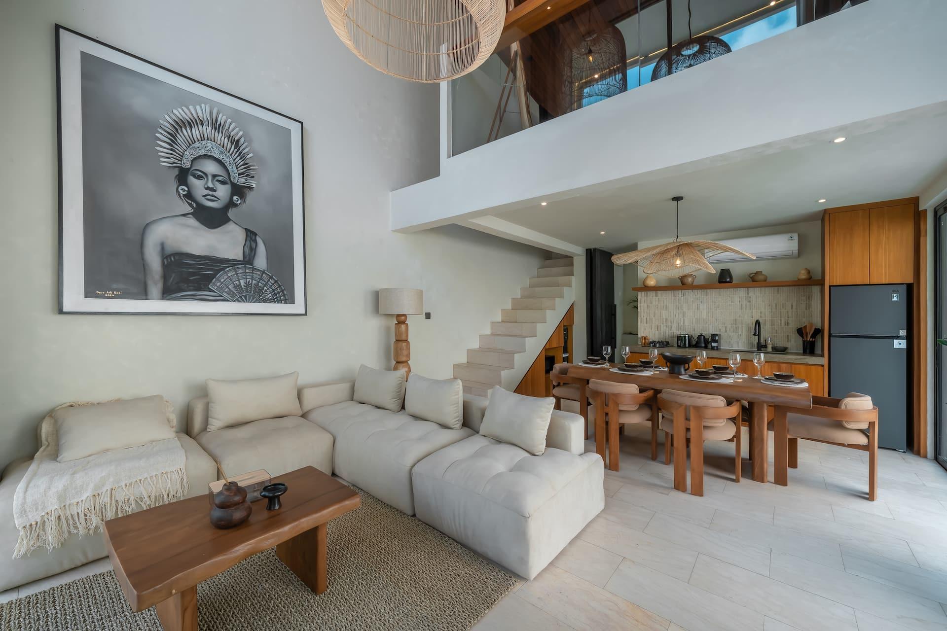 Living room seating and framed portrait artwork below the mezzanine at Villa Elementa