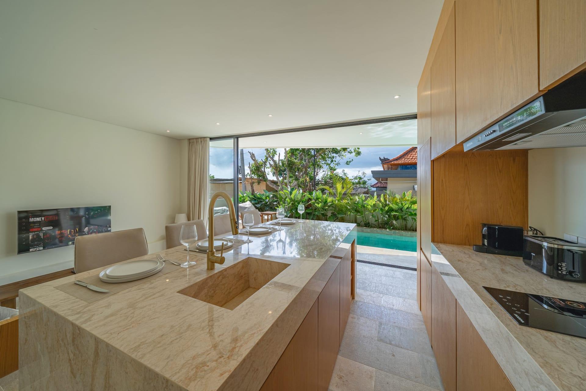 Kitchen island and cooktop at Villa Aura with the pool visible through the glass wall