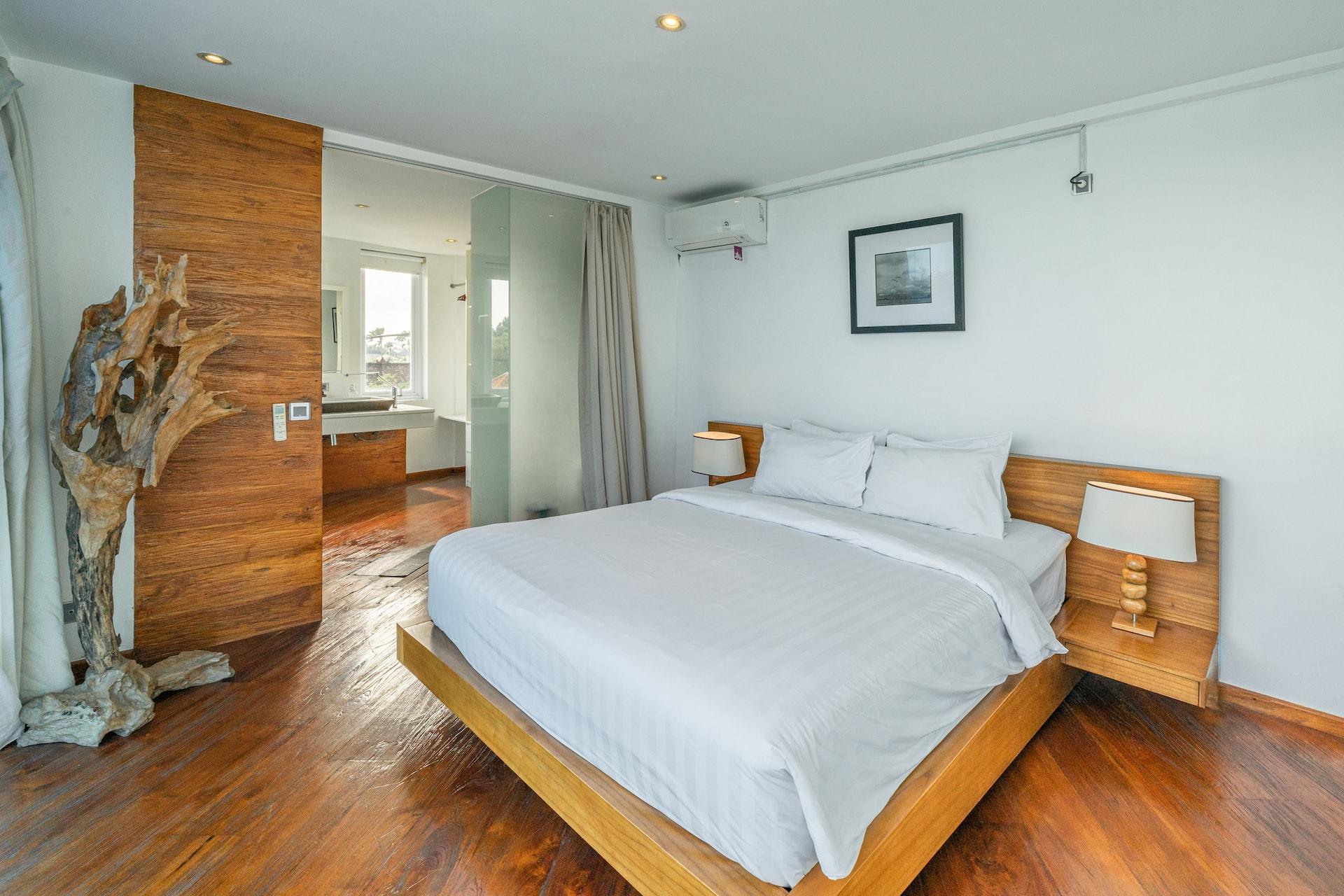 Upstairs bedroom with dark timber floors and a driftwood partition screening the bathroom