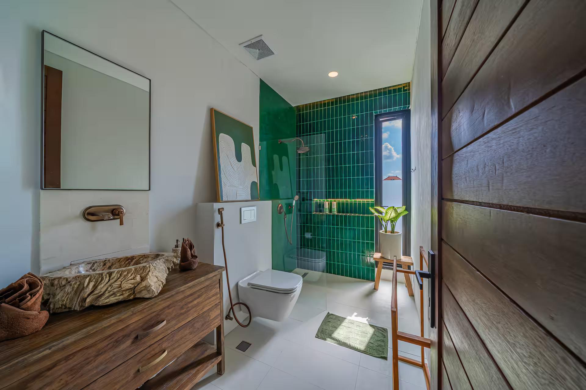 Bathroom in emerald mosaic tile with a hollowed timber-log basin and a solid timber door