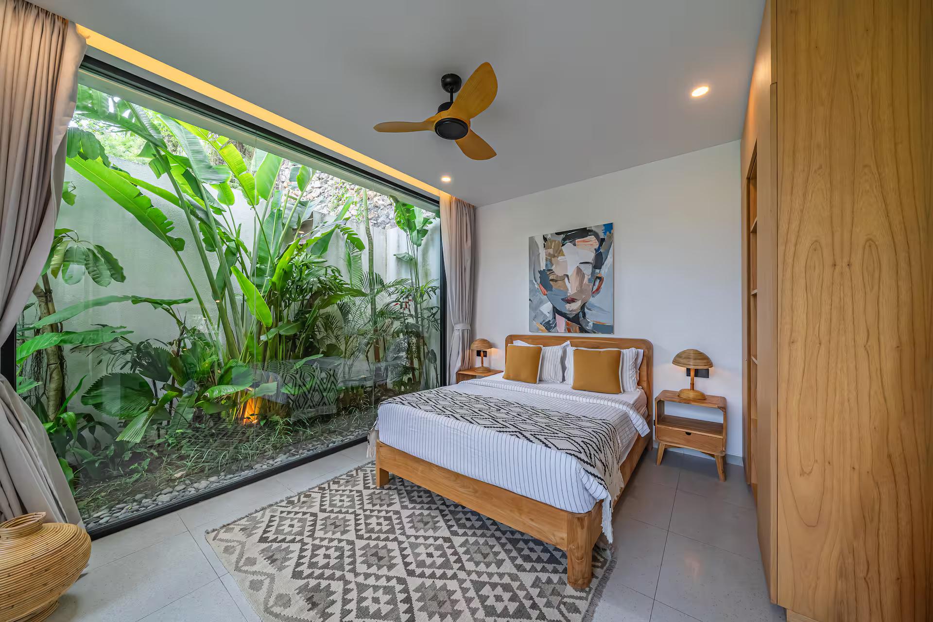 Bedroom with a solid timber bedhead and a full wall of glass onto a planted light court