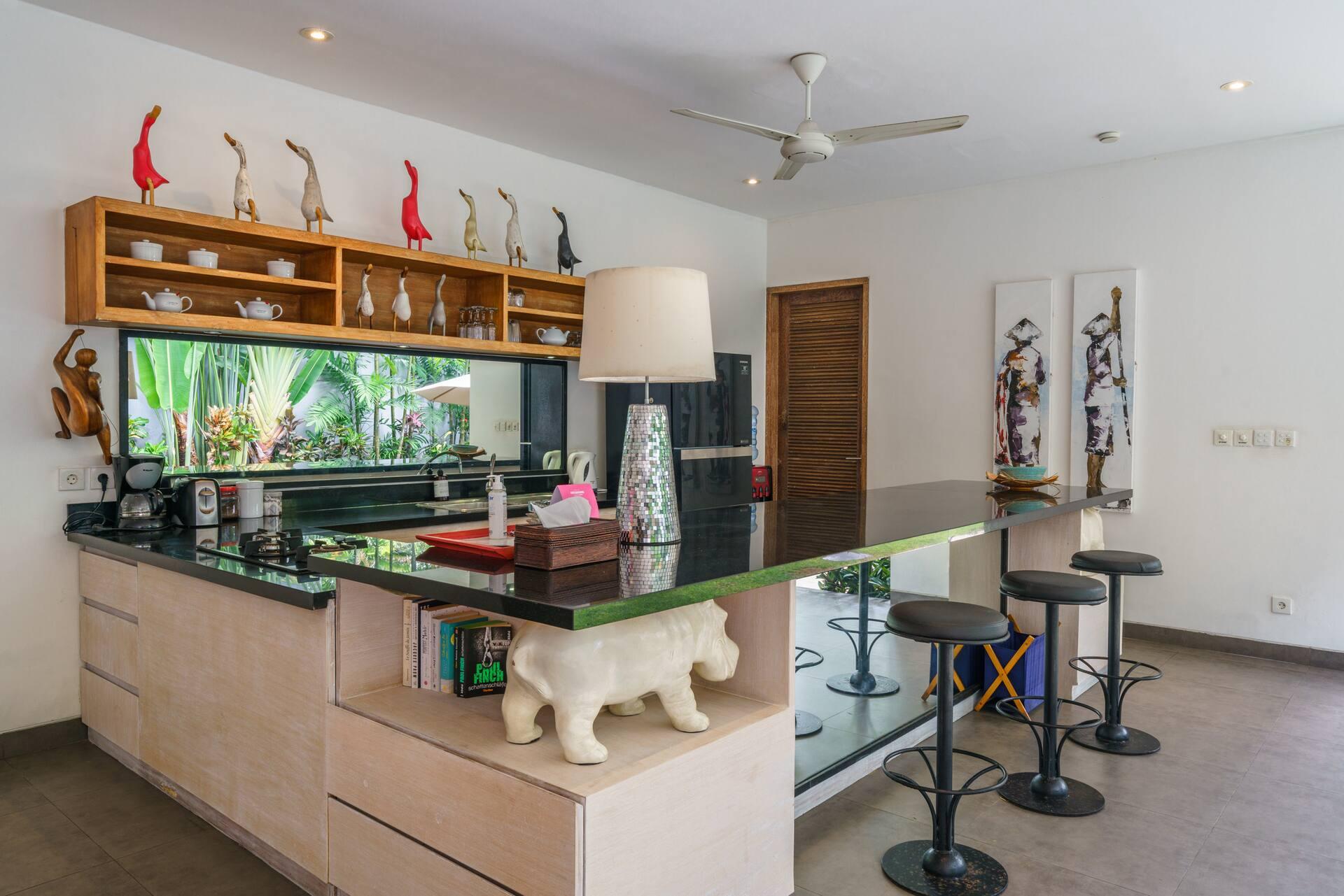 Bar counter in dark stone with stools, red bird figurines above and a stone rhino below