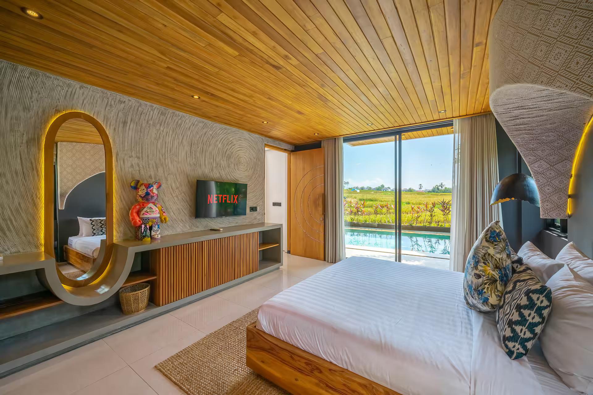 Bedroom with an arched mirror, timber console and a picture window onto the paddy fields