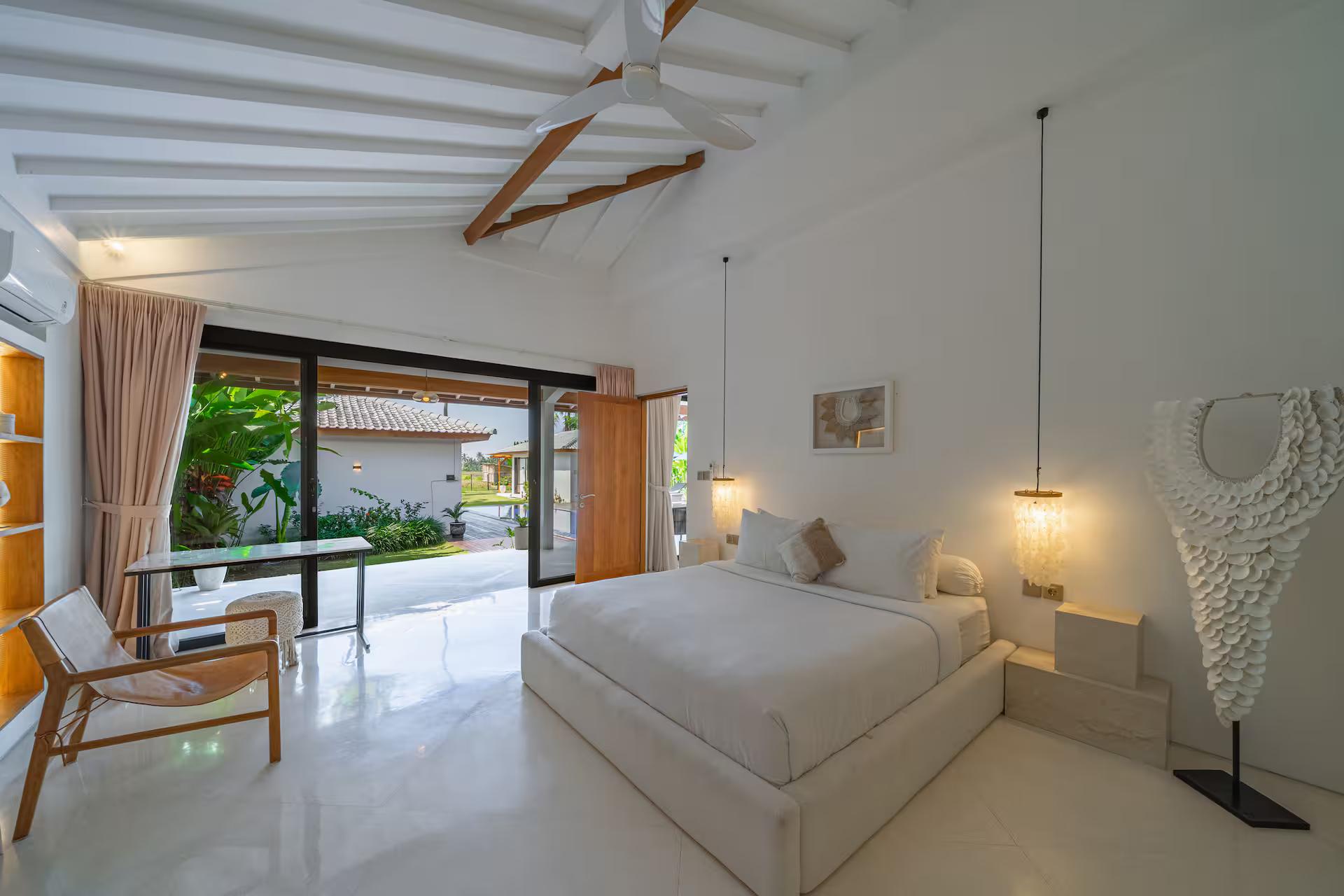 Bedroom with a writing desk, pendant reading lights on long cords and doors to the garden