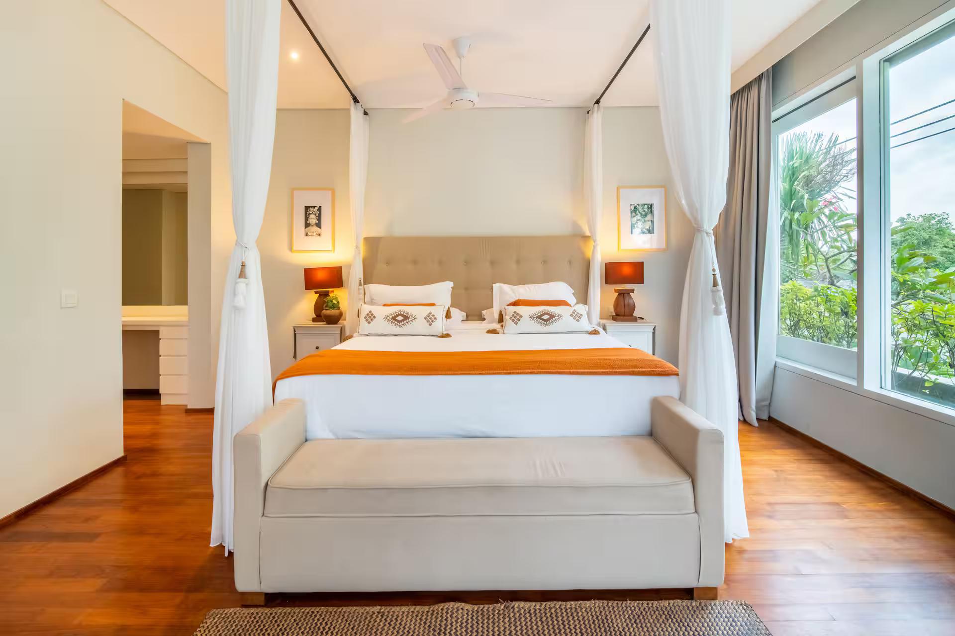 Bedroom with a four-poster king, an orange throw and a day sofa at the foot of the bed