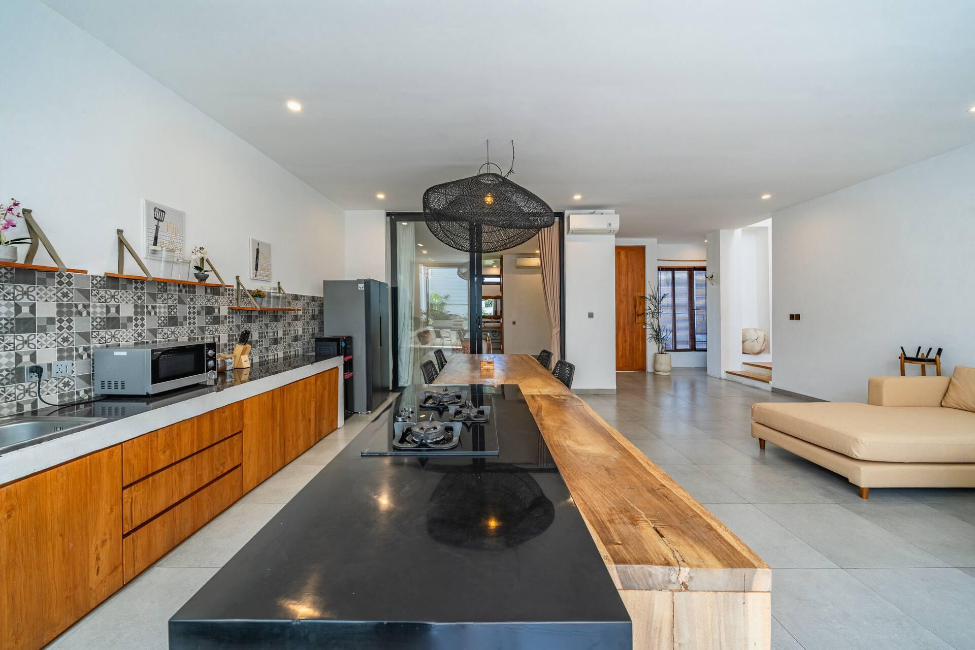 Full length of the open kitchen, its patterned tile splashback running behind the hob
