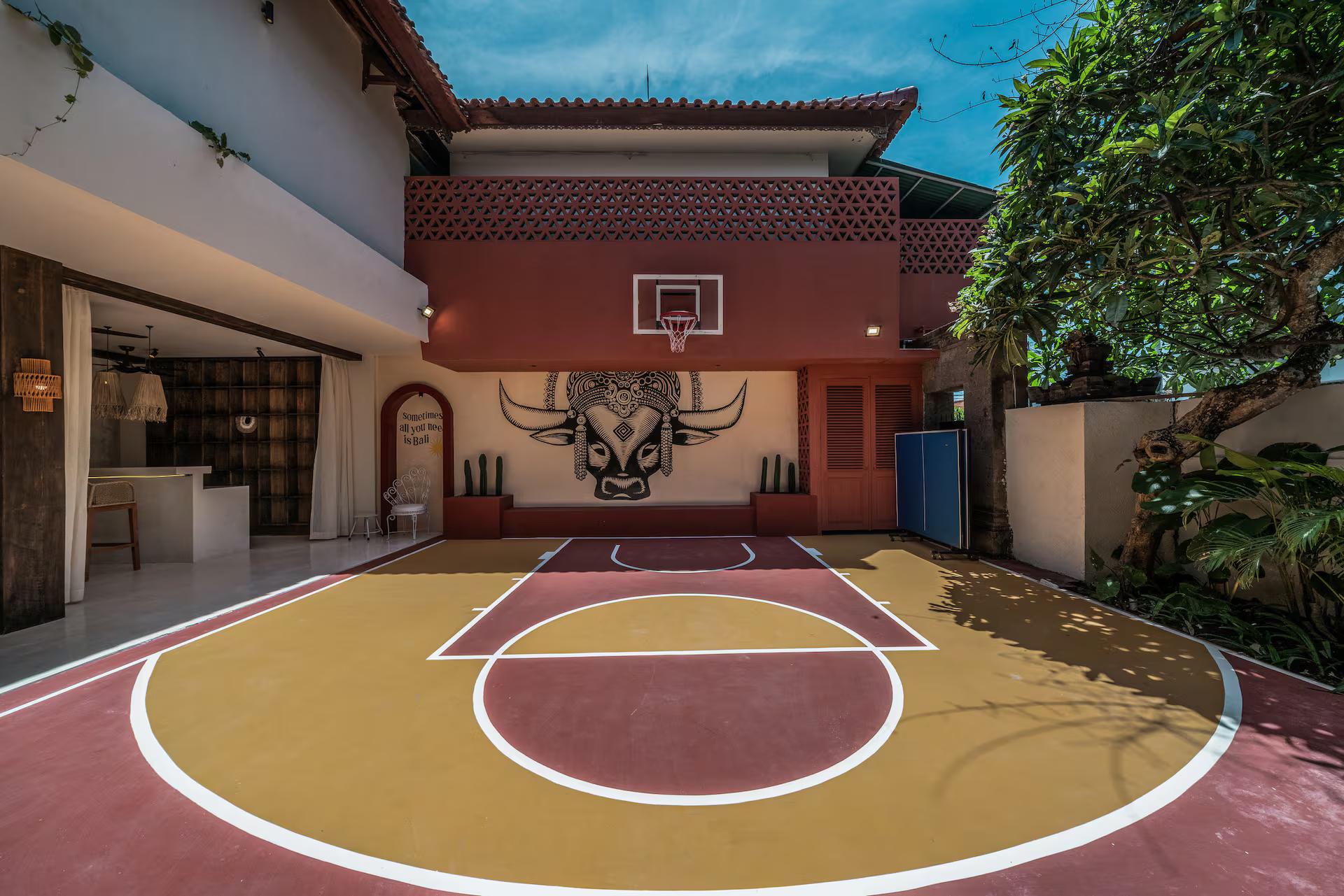 Half basketball court at Casa Galicia, painted red and gold beneath a bull's-head mural