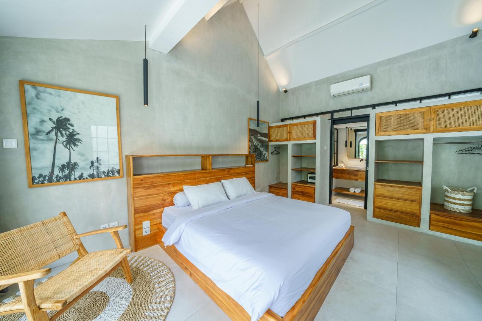 Second king bedroom with a rattan lounge chair, round jute rug and framed surf prints