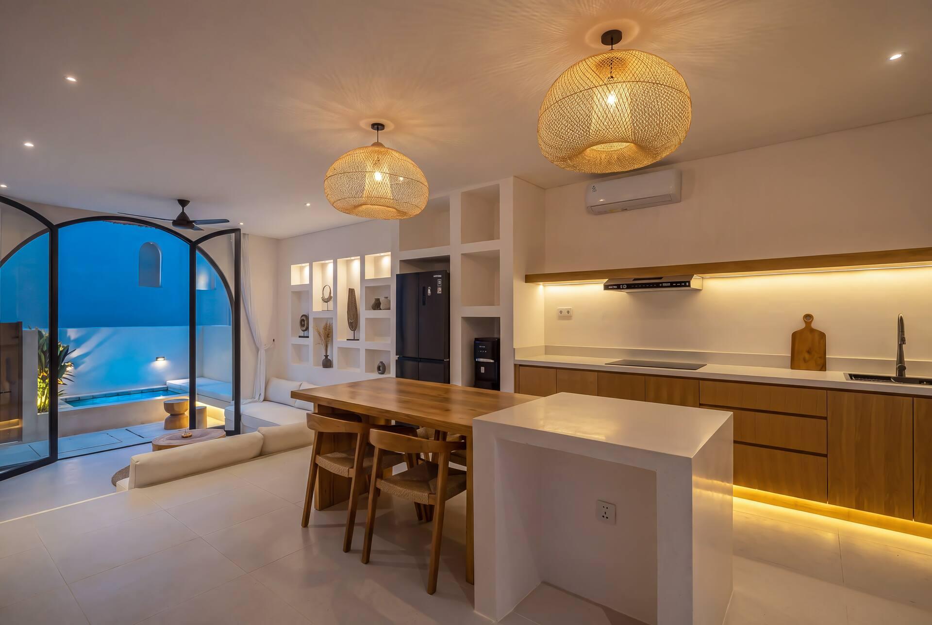 Villa Adiwarna kitchen and dining area glowing at dusk under woven pendant lamps