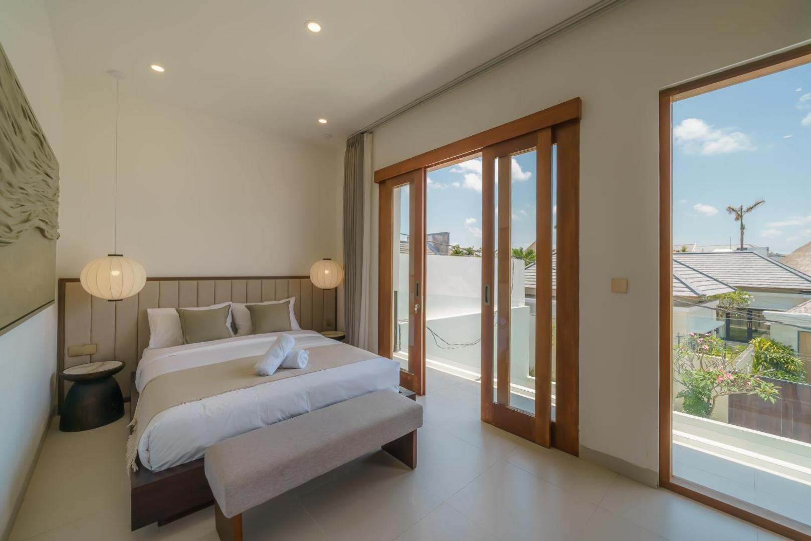 Second king bedroom with paper-globe pendants and timber doors onto a rooftop balcony