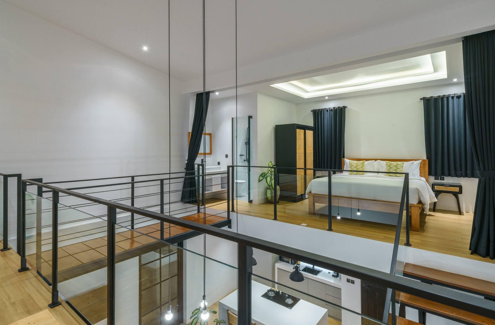 View across the steel-railed mezzanine to the bed, looking down into the living room below